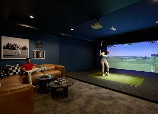 A man is sitting on a couch in front of a large screen playing a video game.