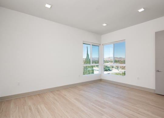 a living room with white walls and wooden floors and large windows