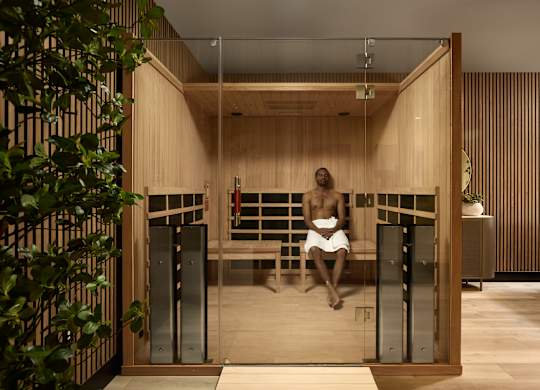 A man is sitting in a sauna with wooden walls and a bench.