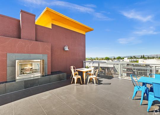 A patio with a table and chairs overlooking a cityscape.