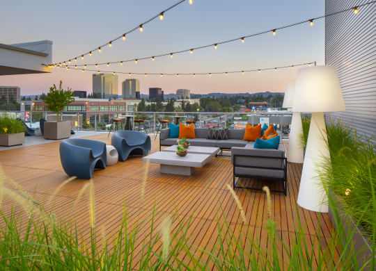 a roof deck with couches and chairs and a city in the background