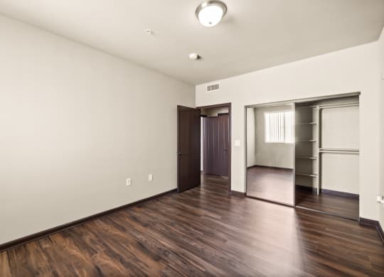 a living room with white walls and wooden floors and a closet at Le Blanc Apartment Homes, Canoga Park, California