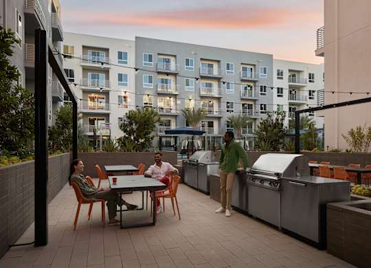 Two people are standing on a patio with a grill.