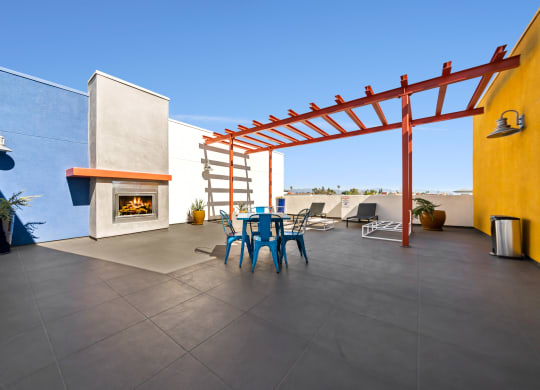 a patio with a blue table and chairs and a fireplace