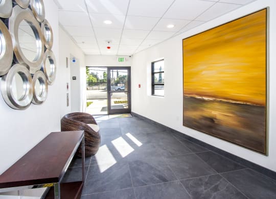 a hallway with paintings on the wall and a table and chairs