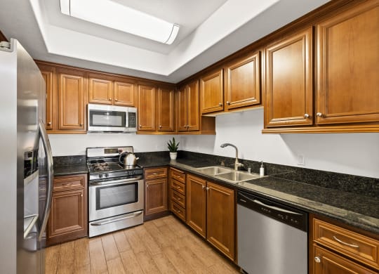 a kitchen with wooden cabinets and stainless steel appliances at Le Blanc Apartments, Canoga Park, CA, 91304