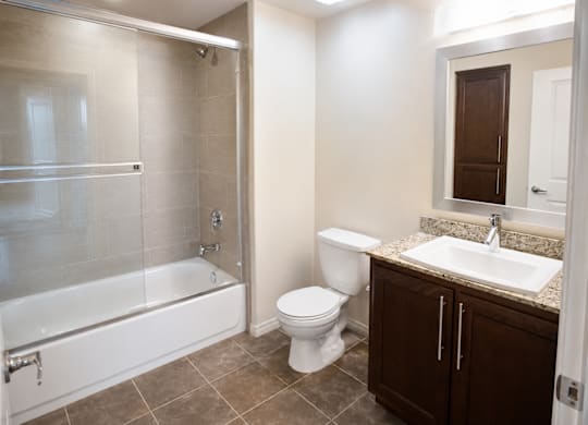 A bathroom with a white toilet, a sink, and a glass shower stall.