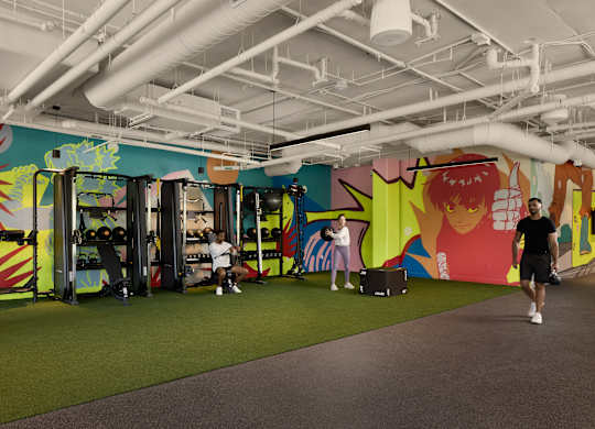 A man is walking in a room with a colorful mural on the wall.