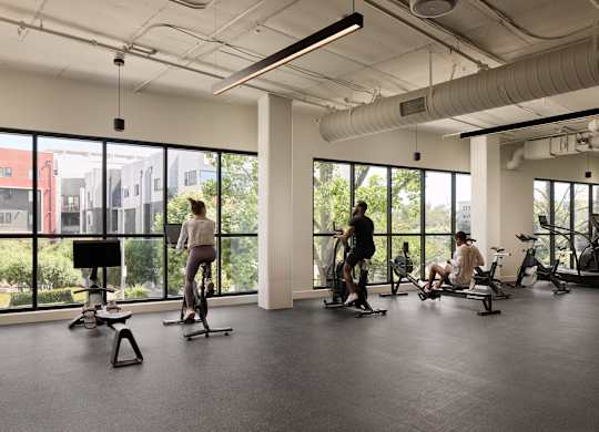 A gym with people exercising and a view of the city.