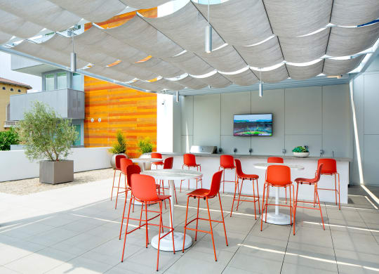 a dining area with red chairs and tables under a white canopy