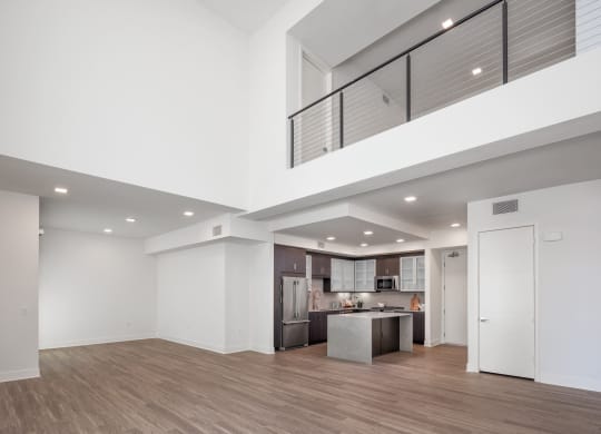 a living room and kitchen with white walls and wood floors