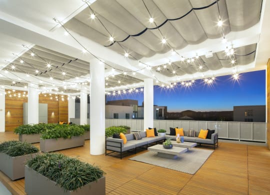 Woodland Hills, CA Apartments - The Q Variel - Penthouse Rooftop with Sofas, Plant Beds, String Lights, Wood-Style Floors and Walls, a TV, and City Views