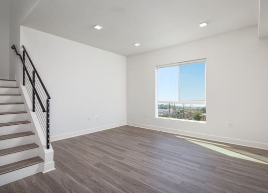 an empty living room with a large window and stairs
