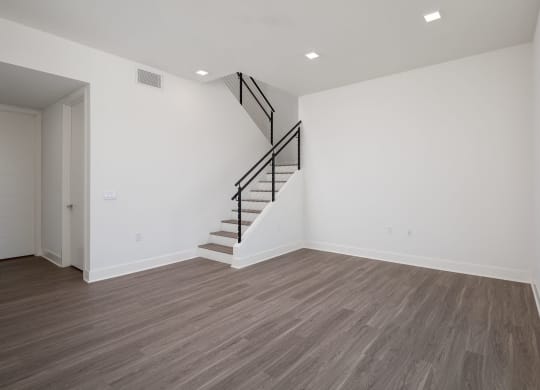 an empty living room with white walls and a staircase in the corner