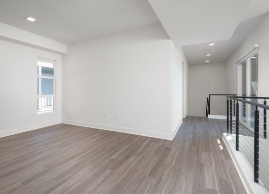 a living room with white walls and wood flooring and a staircase