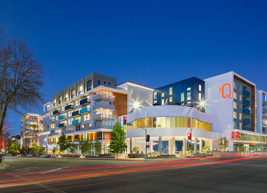 A modern building with a large white circular entrance is illuminated at night.