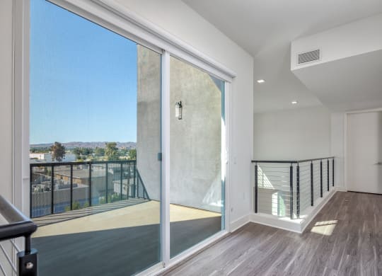 a large glass door opens to a balcony with a view of the city