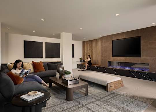 A woman is sitting on a couch reading a book in a modern living room.