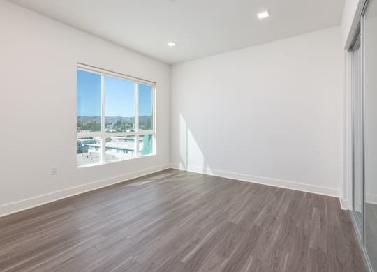 an empty living room with a window and wood flooring