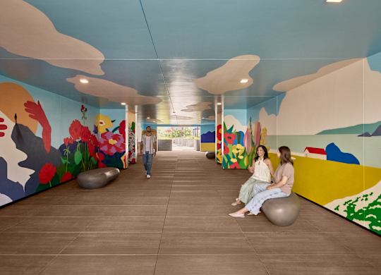 Two women sitting on exercise balls in a room with colorful murals.