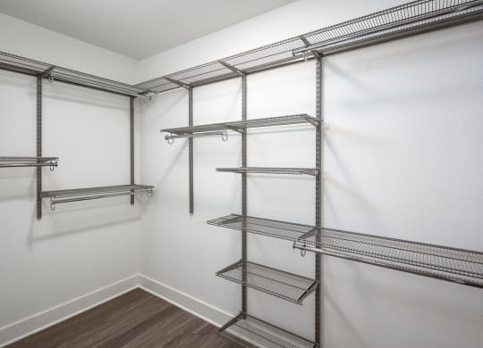 a spacious walk in closet with empty shelves and white walls