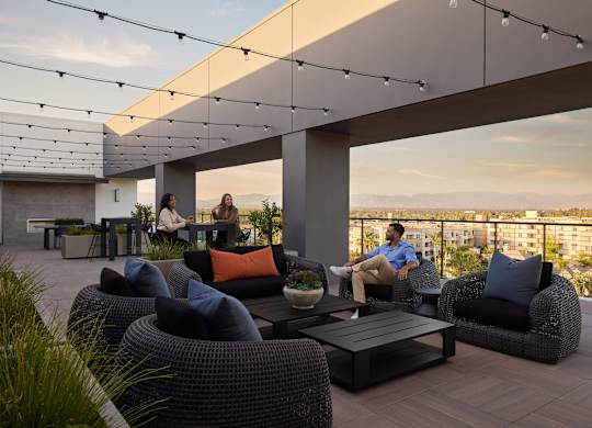 A group of people are sitting on a patio with a view of the city.