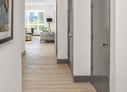 a long hallway with white walls and wood flooring and grey doors