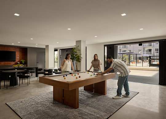 A man is playing pool with two women in a modern room.
