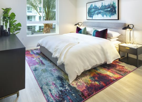 a bedroom with a bed and a rug in front of a window
