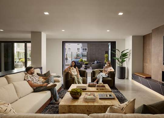 Three people are sitting on a couch in a modern living room.