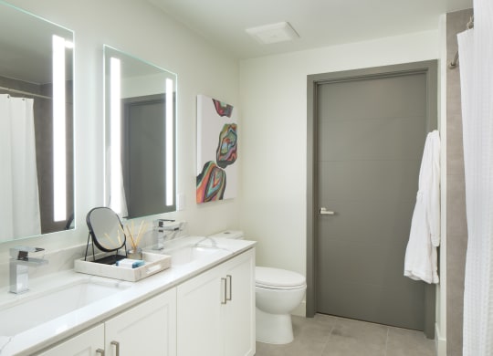 a white bathroom with two sinks and a toilet