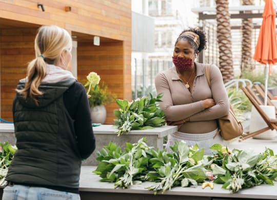 two women standing in front of a flower shop with plants