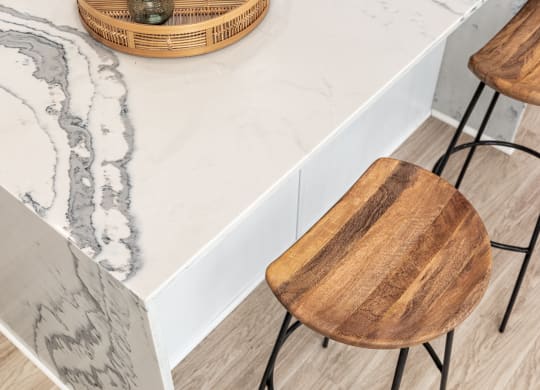 a kitchen with marble counter top and wooden chairs