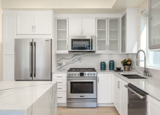 a white kitchen with stainless steel appliances and white cabinets