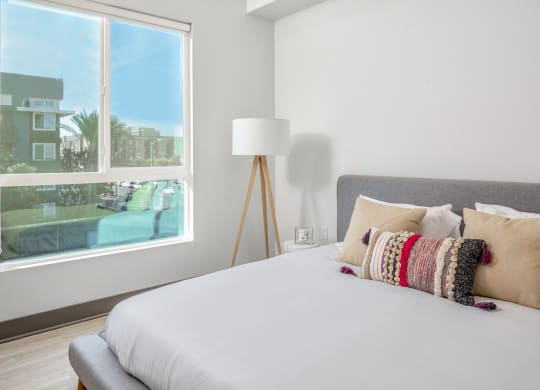 a bedroom with a large window and a bed with pillows