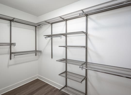 a spacious walk in closet with empty shelves and white walls