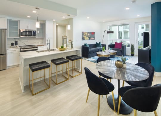Apartments in Woodland Hills, CA for Rent - The Q Variel - Dining Area, Kitchen, and Living Room with an Open-Concept Layout, Luxury Wood Plank Style Flooring, High Ceilings, Modern Light Fixtures, and Expansive Windows