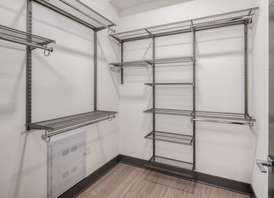 a walk in closet with empty shelves and a door