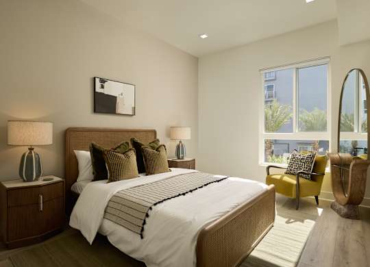 A bedroom with a large bed, two lamps, and a chair.