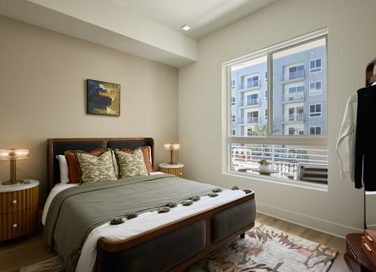 A bedroom with a large bed and a window overlooking a cityscape.