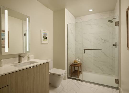 A bathroom with a marble shower and a wooden vanity.
