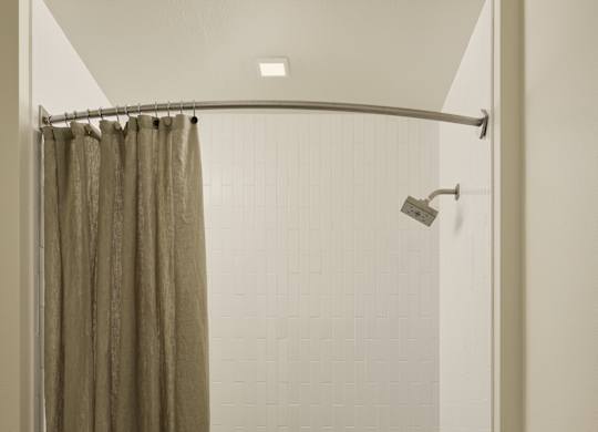 A bathroom with a shower curtain and a towel hanging on the door.
