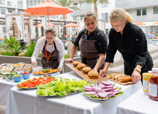 three women in aprons preparing food on a table