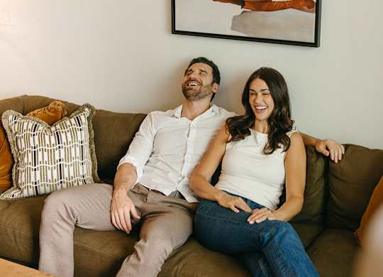 A man and woman are sitting on a brown couch.