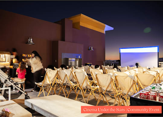 A group of people are sitting in chairs outside watching a movie.