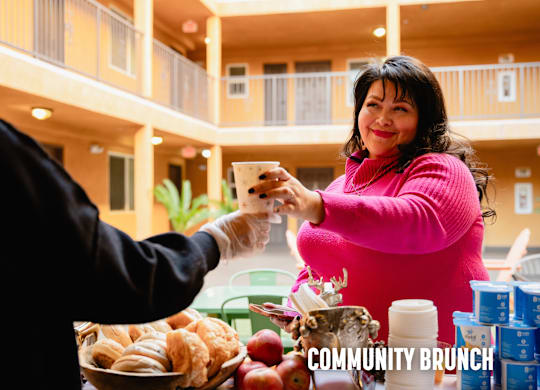 A woman in a pink sweater is serving food to a man in a black jacket.