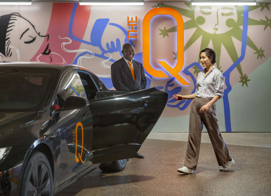 a man and a woman standing next to a black car