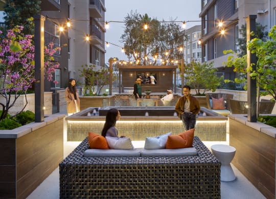 a couple sitting on a couch in front of a pool in an apartment complex