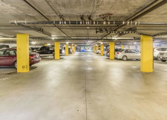 a parking garage with cars and yellow pillars at Dronfield Astoria Apartments, Sylmar