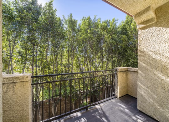 balcony with iron fence looking out to green trees at The Village Apartments, Van Nuys